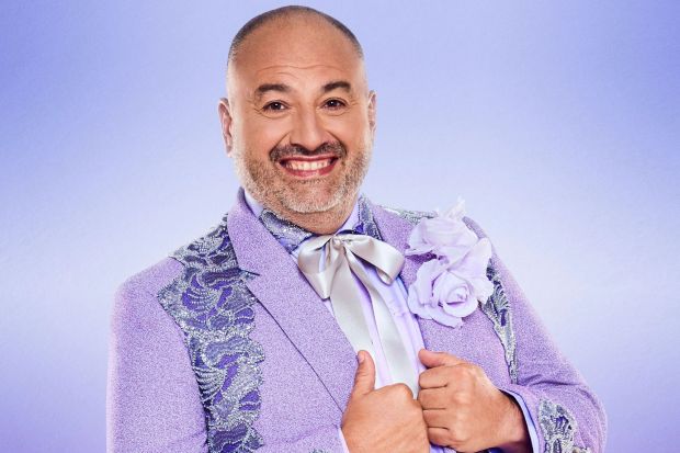 Portrait of a smiling man in a lavender suit.