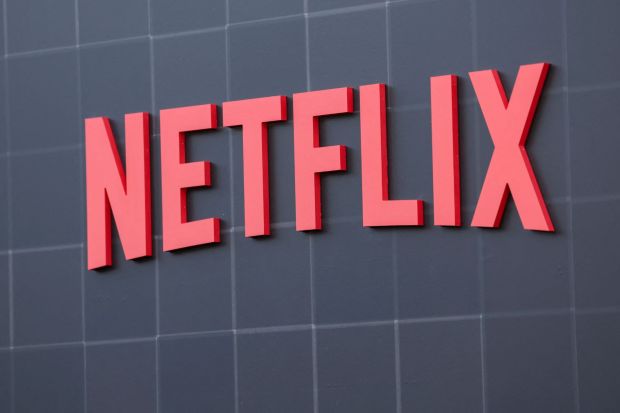 Netflix logo on a dark gray wall.