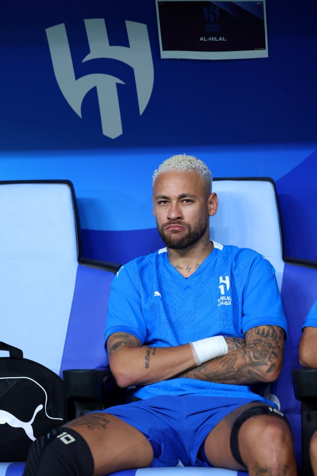 Neymar of Al-Hilal sits on the bench with arms crossed.