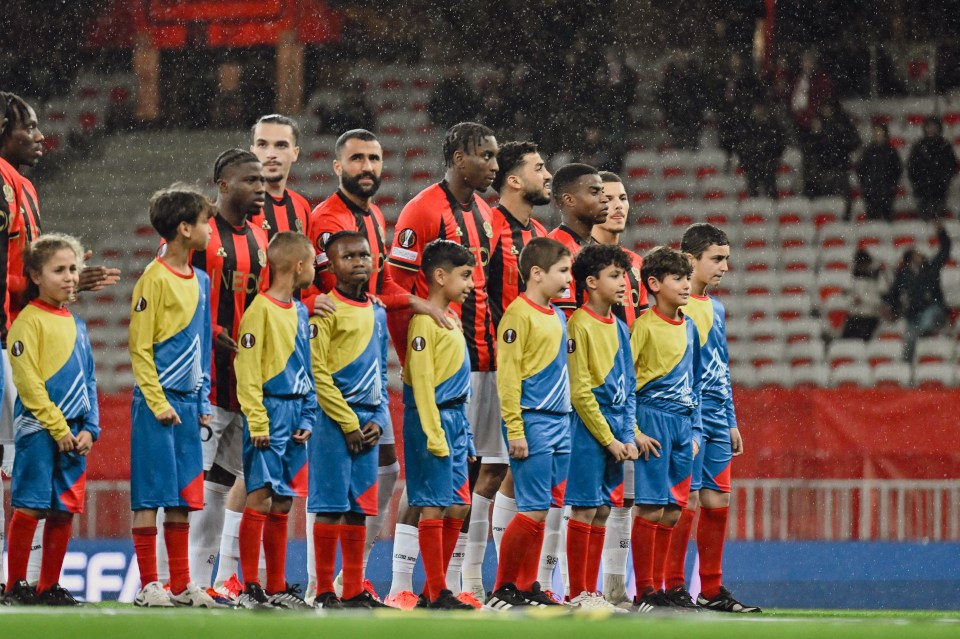 OGC Nice soccer players and young ball boys line up on the field.