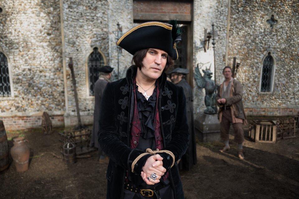 Noel Fielding, hands bound, in period costume.