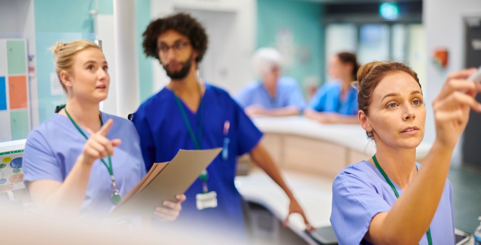 Nurses and doctors collaborating at a hospital nurses' station.