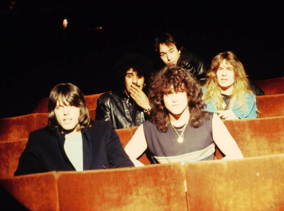 Photo of Thin Lizzy band members seated in a theater.