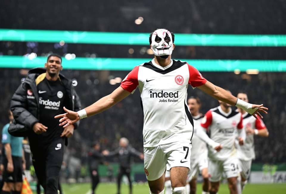 Soccer player Omar Marmoush of Eintracht Frankfurt celebrating a goal while wearing a mask.