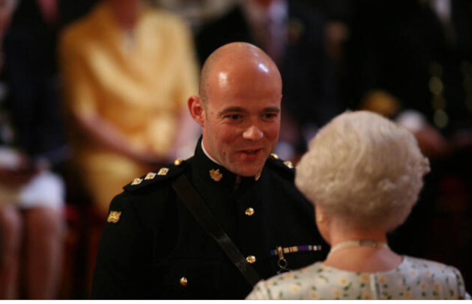 A British army officer receives the Queen's Gallantry Medal from Queen Elizabeth II.