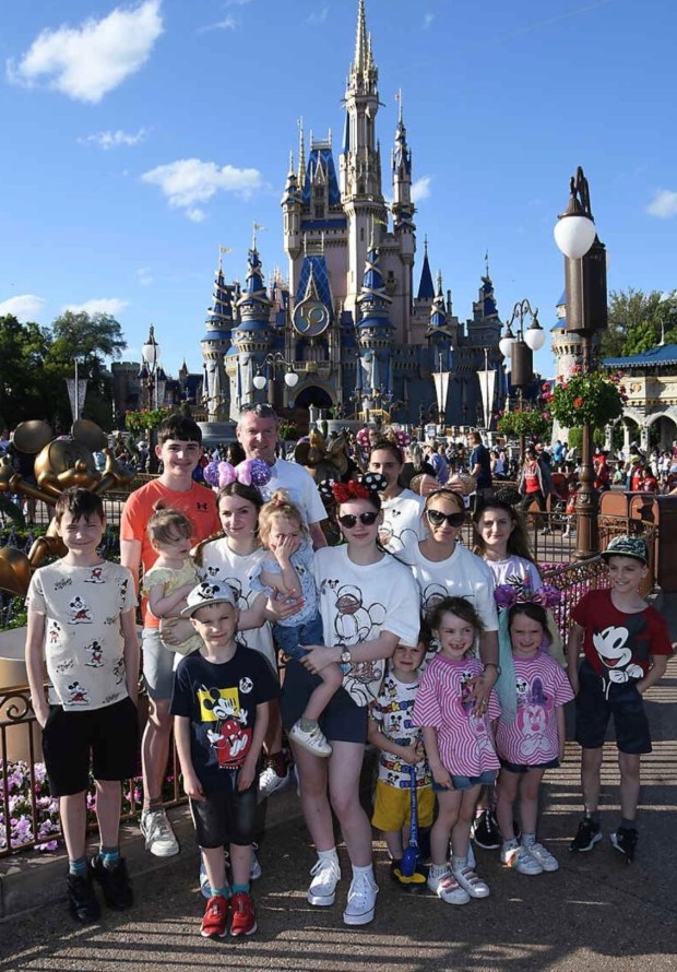 Large family posing in front of Cinderella Castle at Disney World.