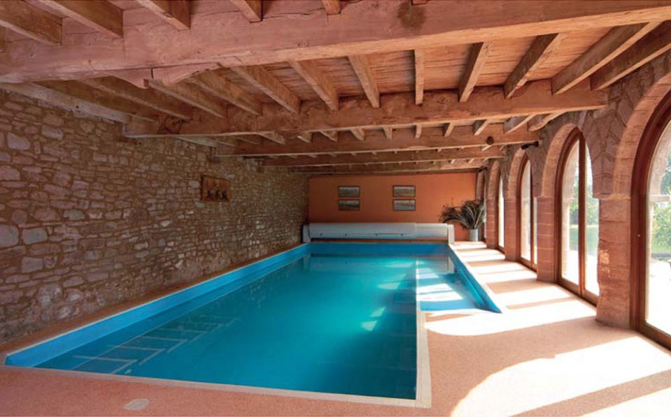 Indoor swimming pool in stone building with wooden beams.