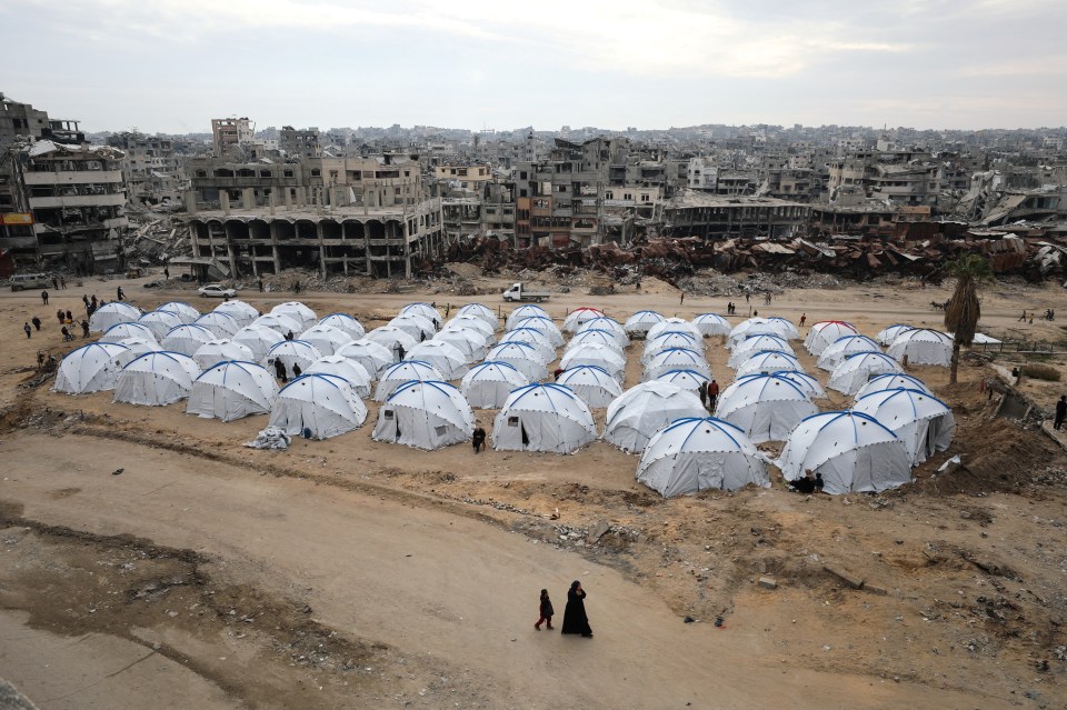 Tent camp in Gaza City amidst destroyed buildings.