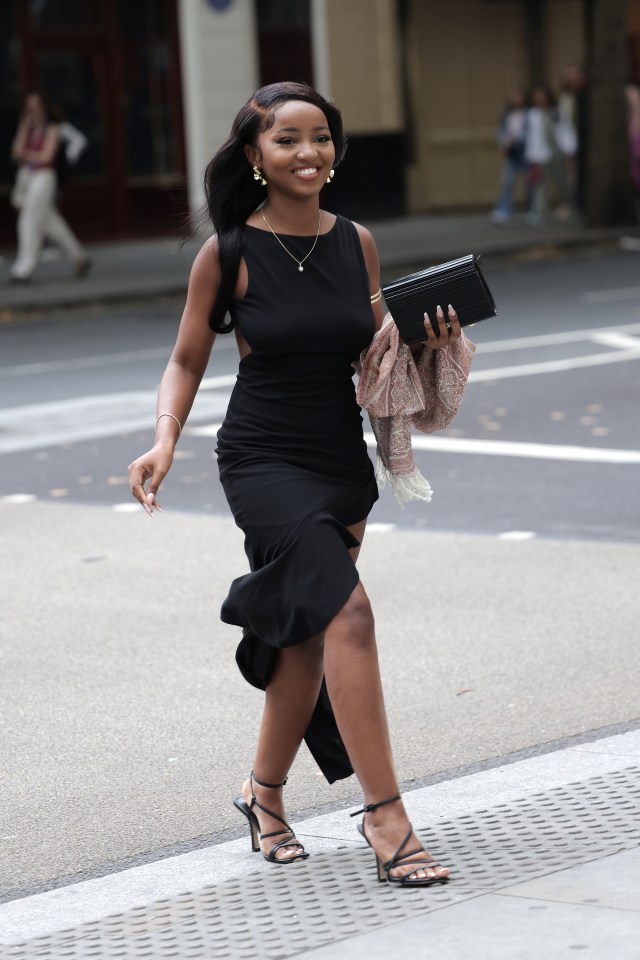 Woman in black dress and heels walking down the street.