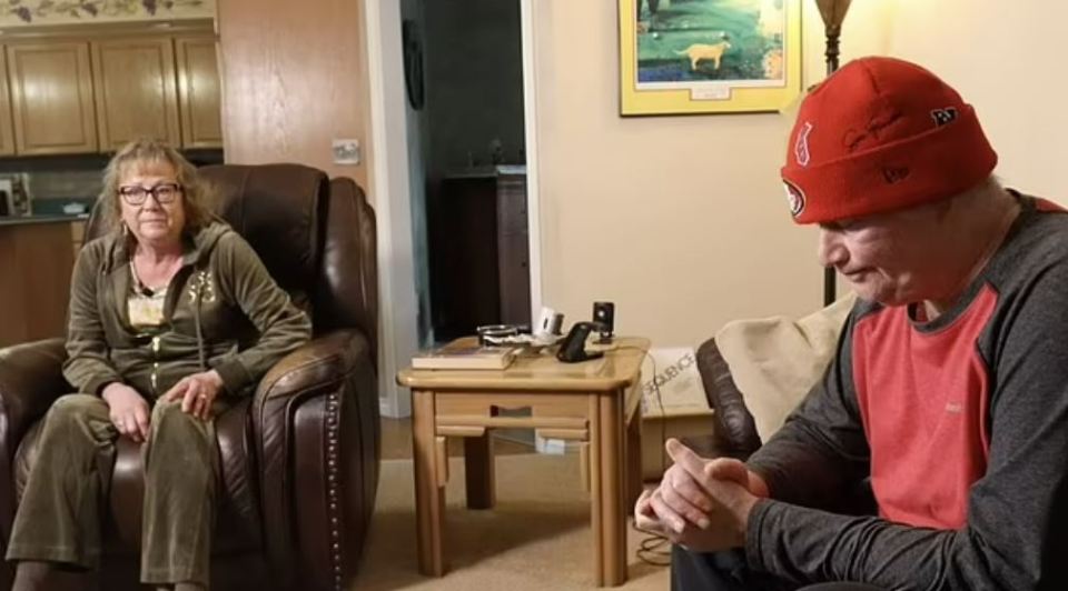 A woman and a man sitting in a living room, appearing distressed.