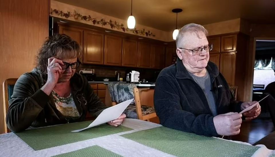 A grieving couple reviewing documents at their kitchen table.