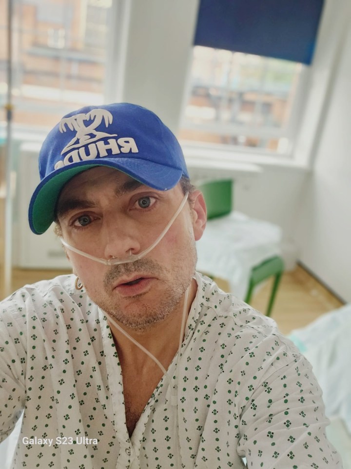 Man in hospital gown and baseball cap using a nasal cannula.