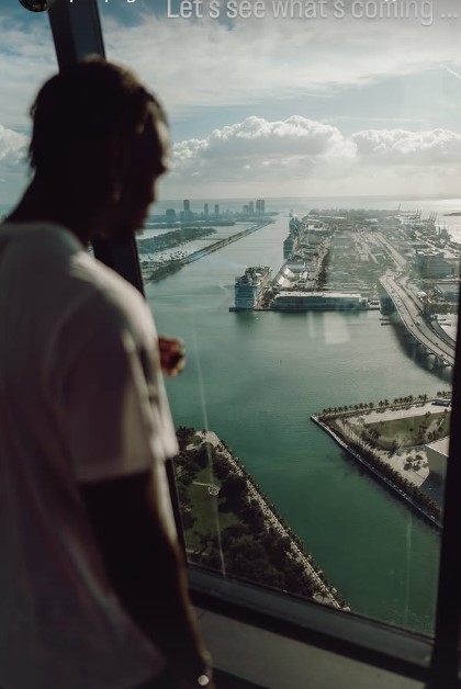 Person looking out a window at a city and waterway.