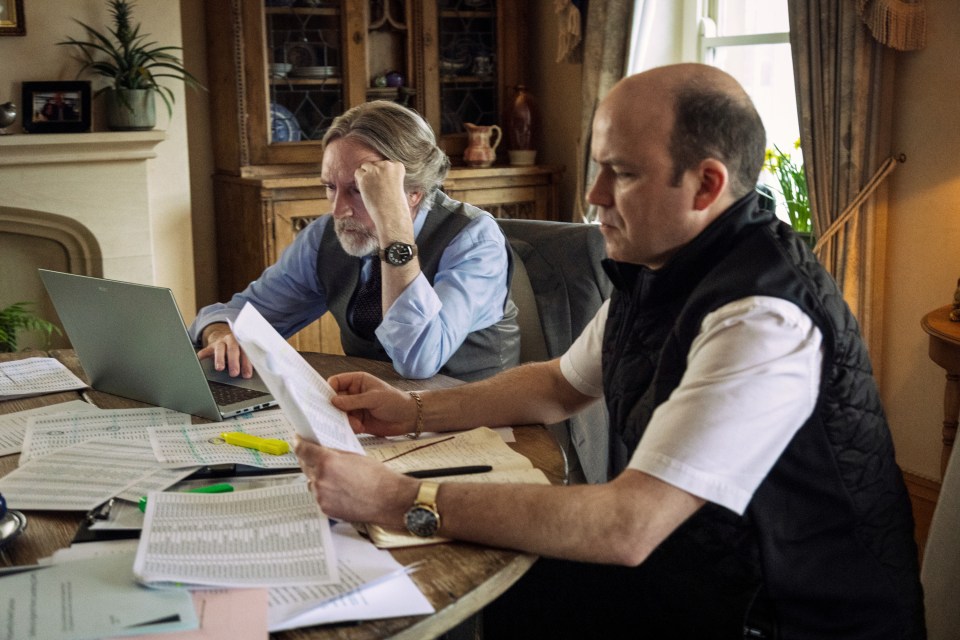 Film still of Pearce Quigley and Rory Kinnear reviewing documents.