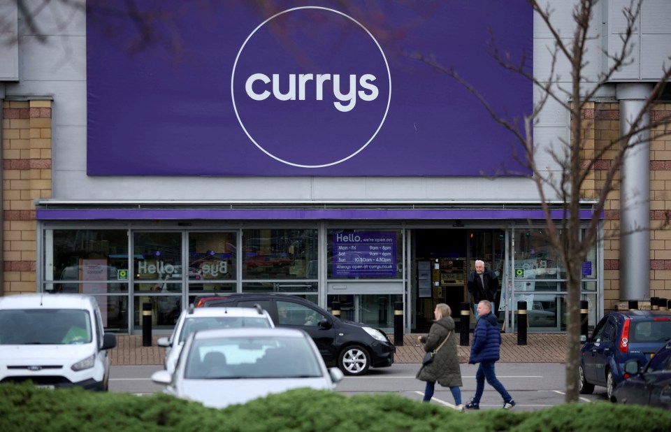 People walking past a Currys electronics store.