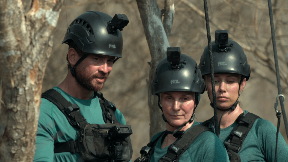 Production still image of three people wearing helmets and harnesses.