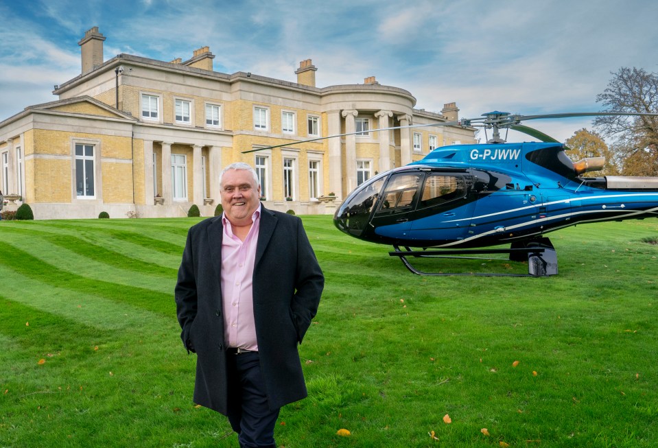 Peter Waddell, a millionaire car supermarket businessman, standing in front of his mansion and helicopter.