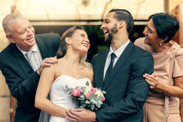 Happy newlyweds with their parents after a wedding ceremony.