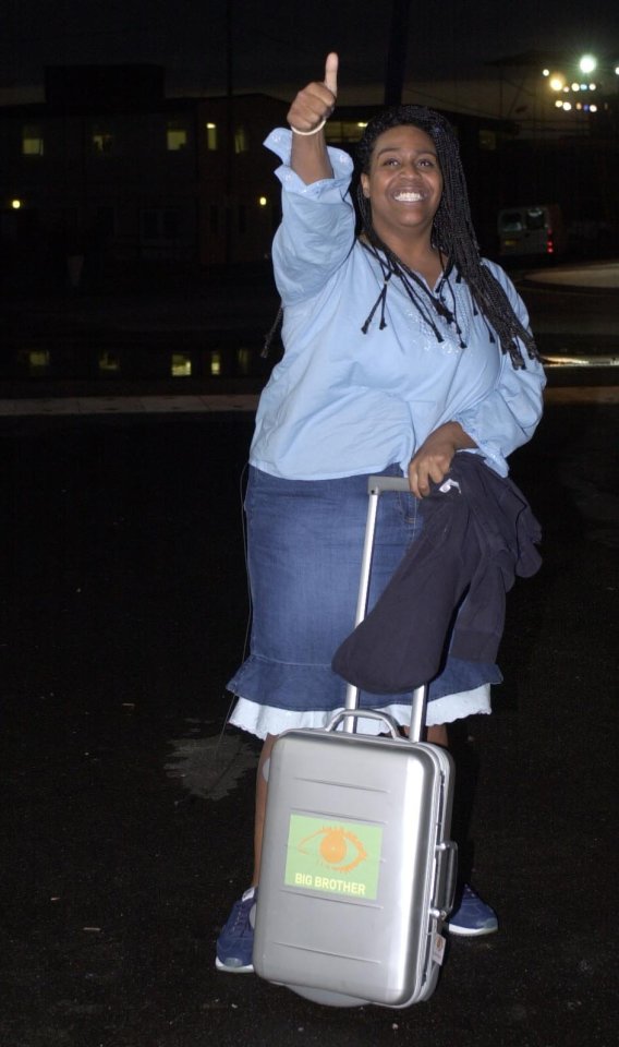 A Big Brother contestant gives a thumbs-up while pulling a suitcase.