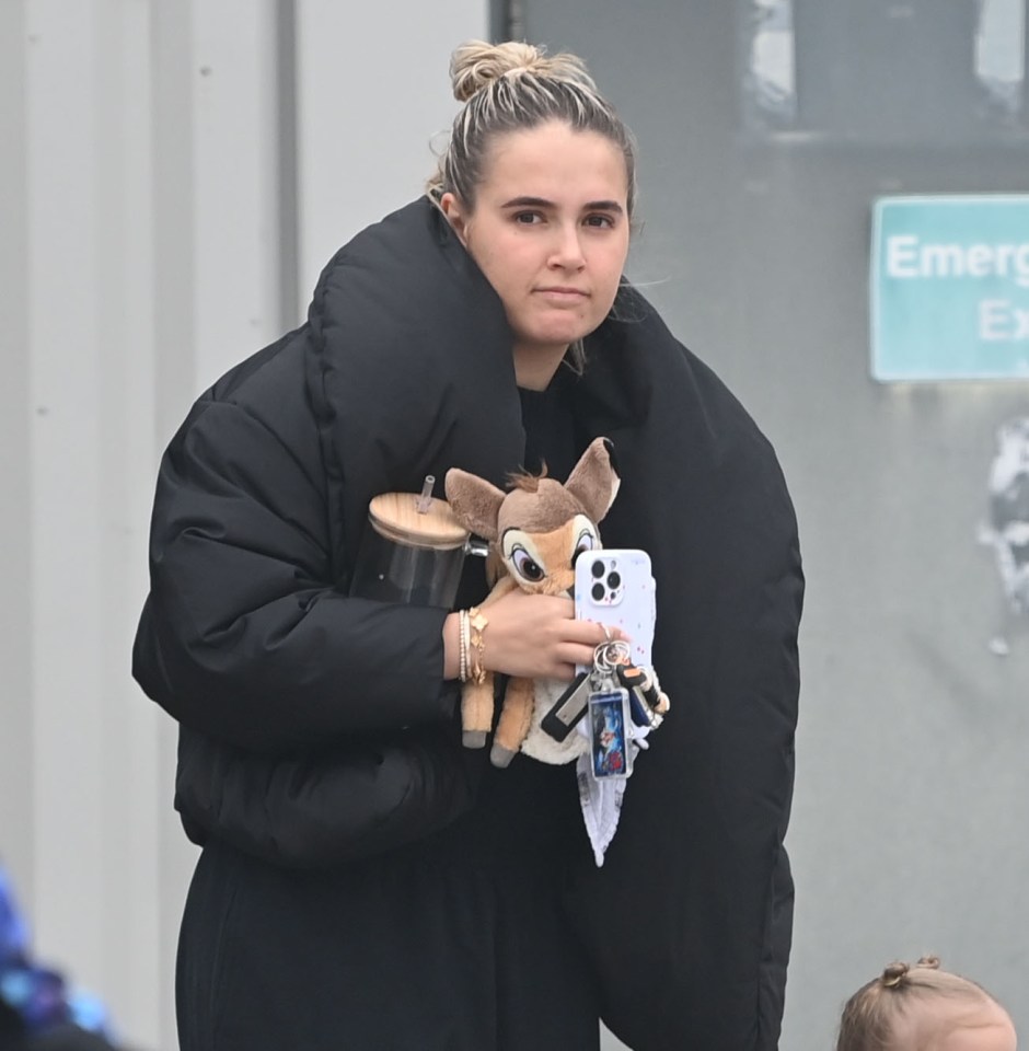 Molly Mae Hague holding a stuffed deer, phone, and drink.