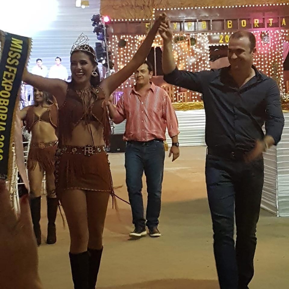 Woman holding Miss Expoborja 2016 sash, celebrating with a man.