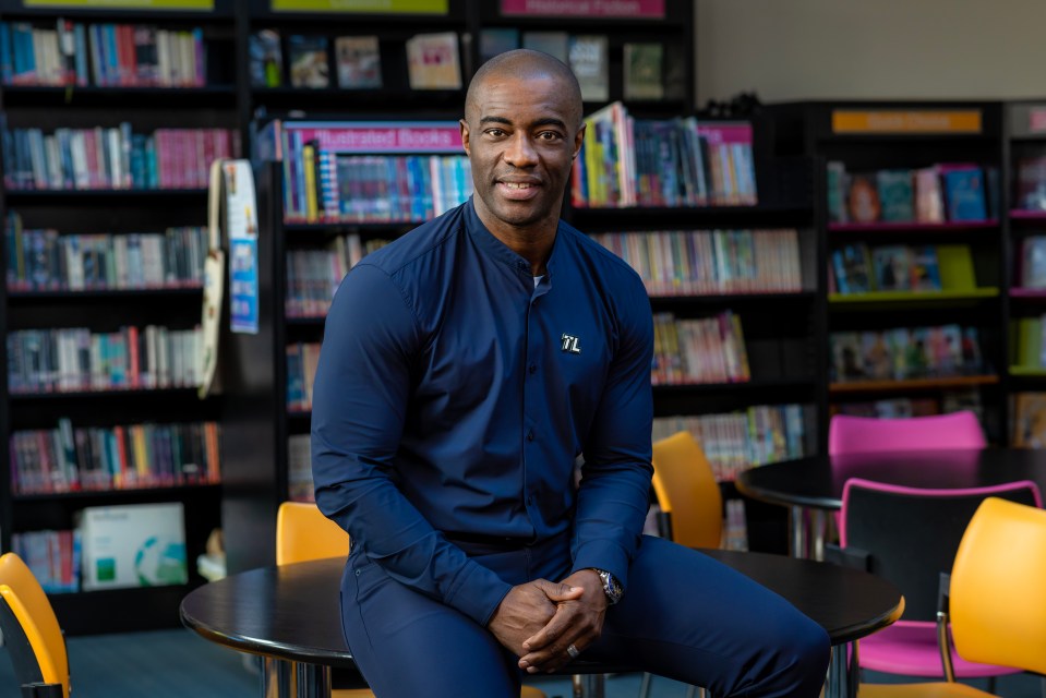 Portrait of Tim Campbell sitting at a table in a library.