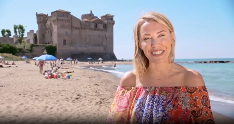 Woman on a beach in front of a castle.