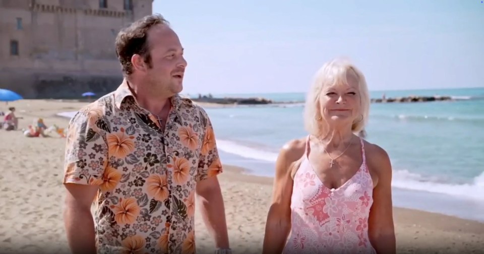 A man and woman walking on a beach.