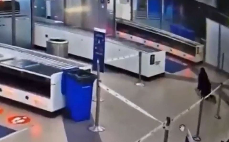 Woman crawling under airport security barrier.