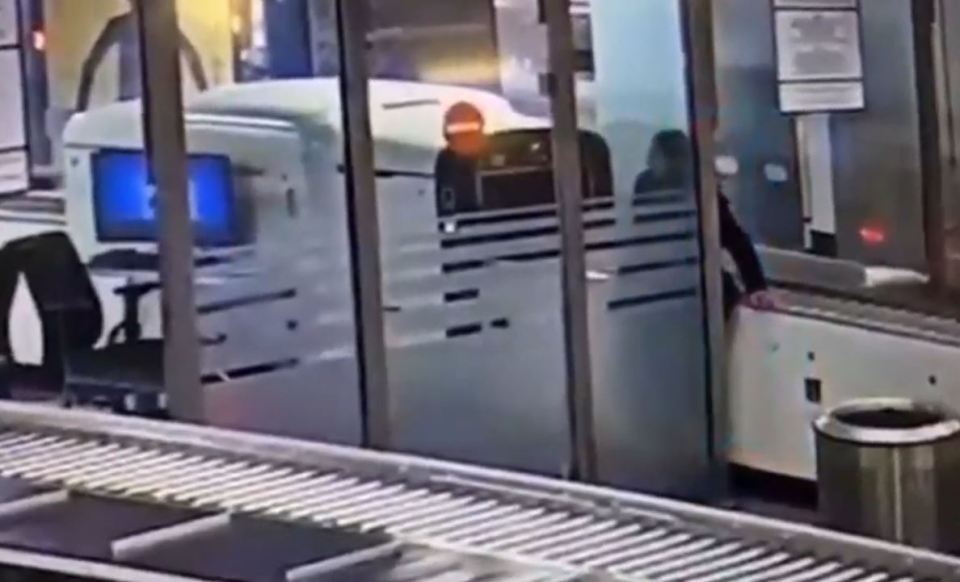 Woman crawling under airport security barrier.