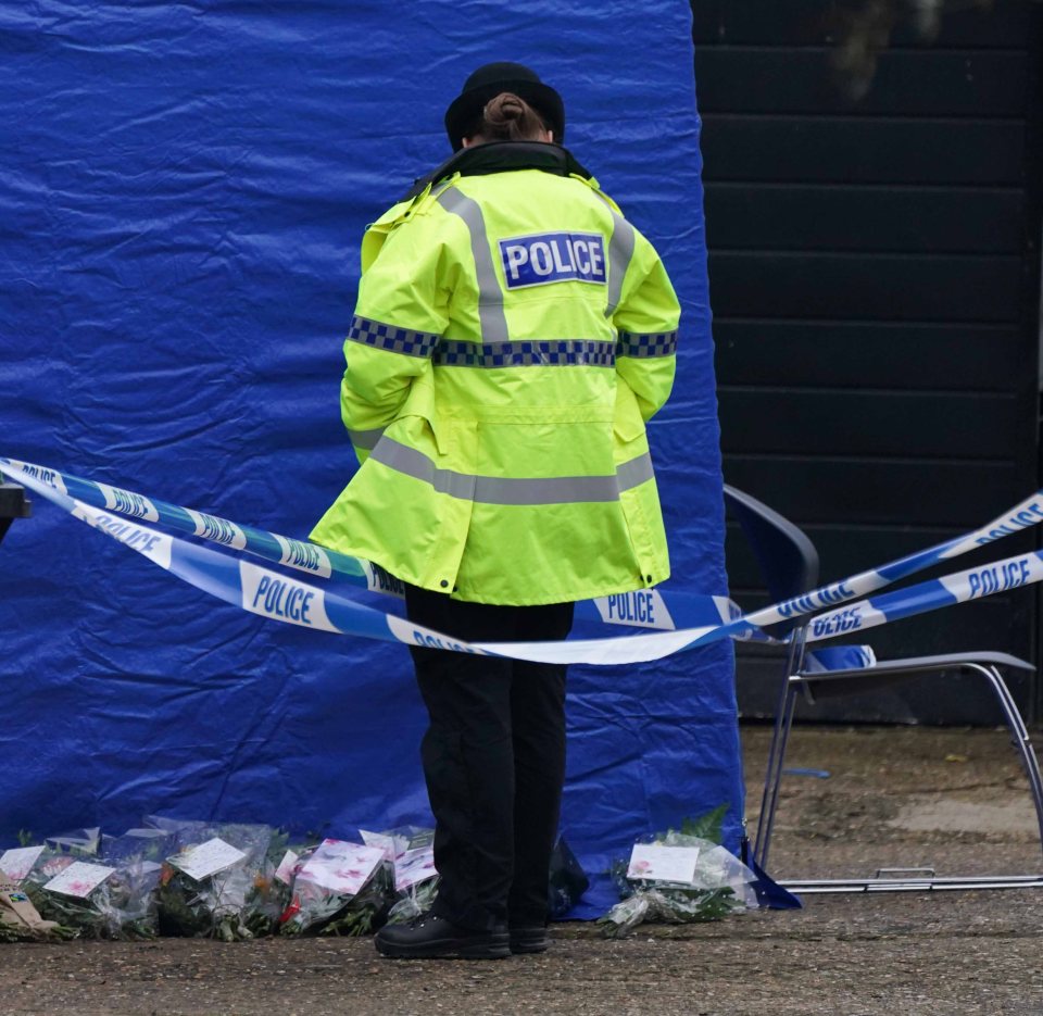 Police officer at a crime scene with flowers.