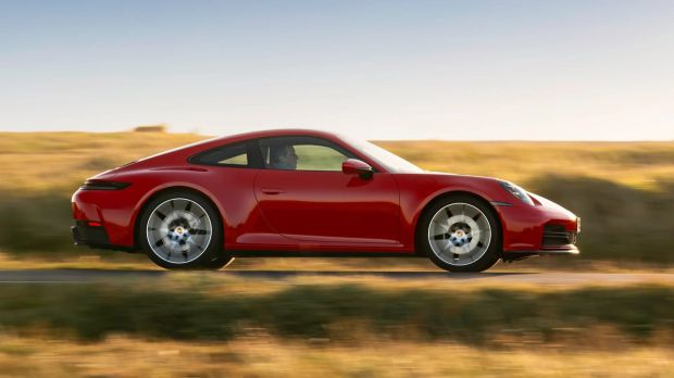 Red Porsche 911 driving on a road.