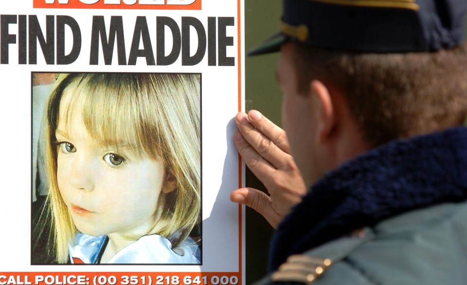 A Portuguese police officer examines a missing person poster for Madeleine McCann.