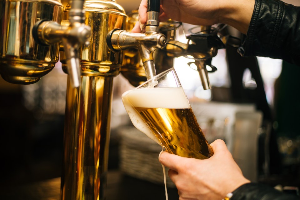 Bartender pouring beer into a pint glass.