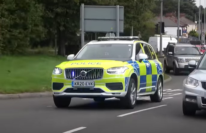 Volvo police car driving on a road.