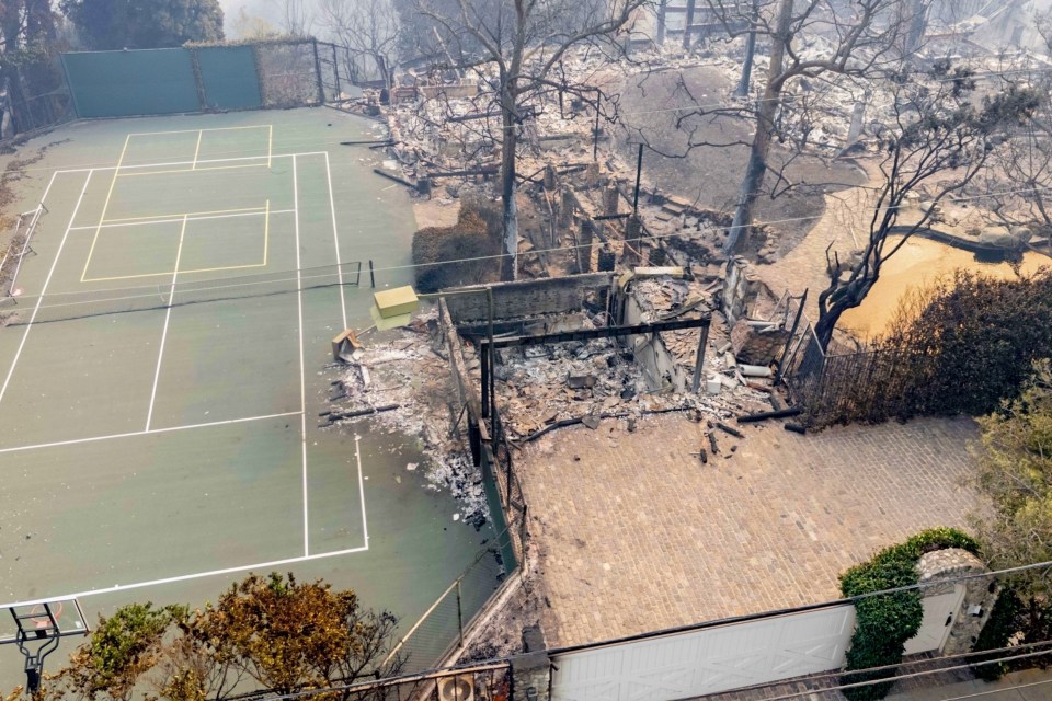 Aerial view of fire damage to Billy Crystal's home, including a destroyed house and a nearby undamaged tennis court.