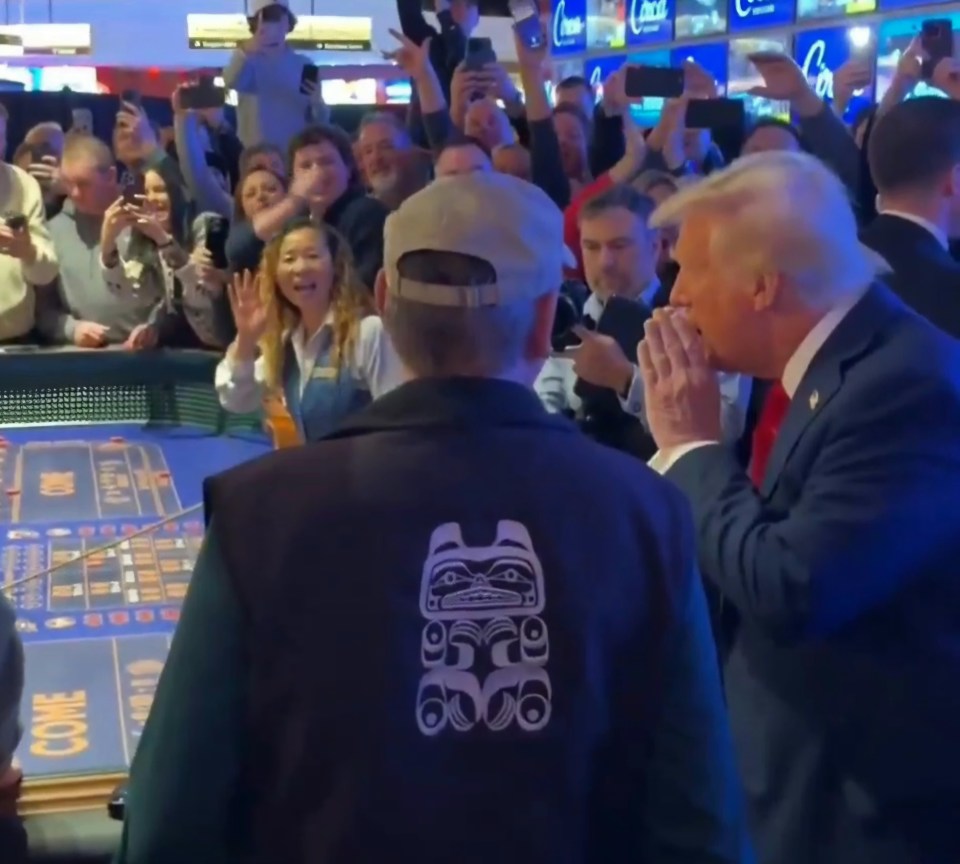 Donald Trump at a craps table in a casino, interacting with players and onlookers.