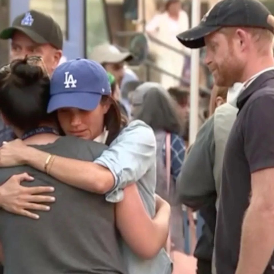 Meghan Markle hugging a person while Prince Harry stands nearby.