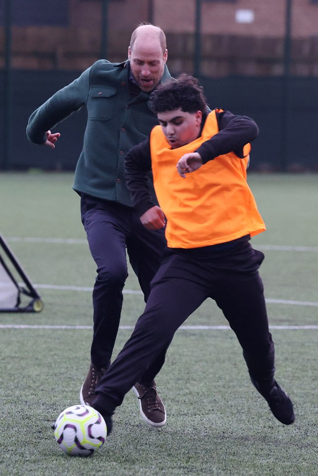 The Prince of Wales playing soccer with a young person.