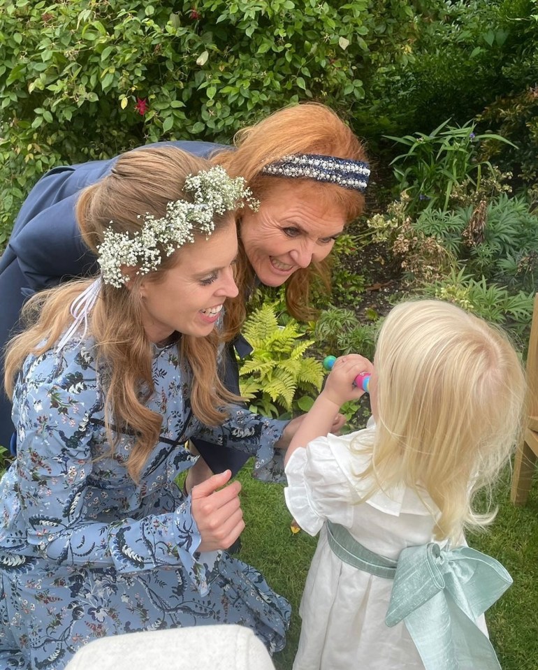 Princess Beatrice, her mother, and a young child together in a garden.