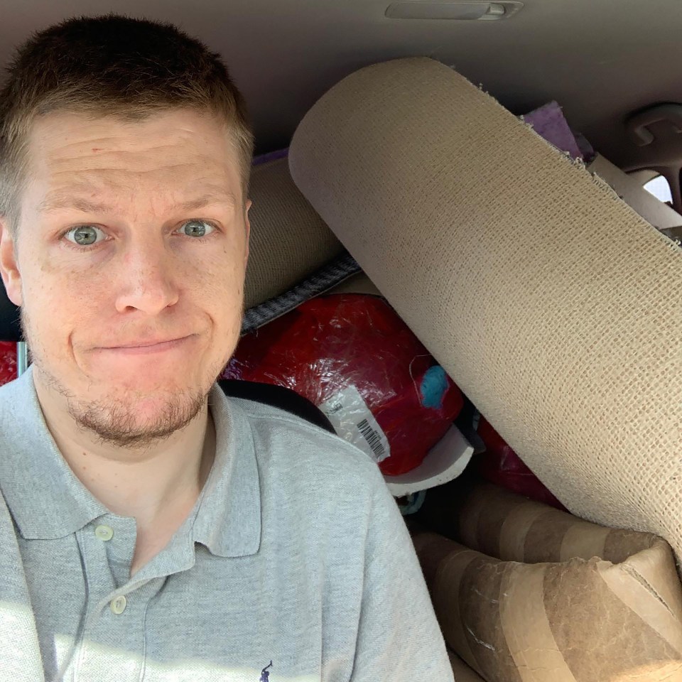 Man in a car with furniture in the backseat.