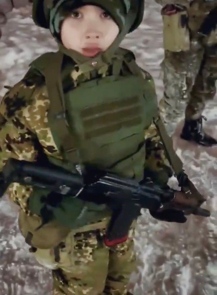 Young child in military uniform holding a rifle.