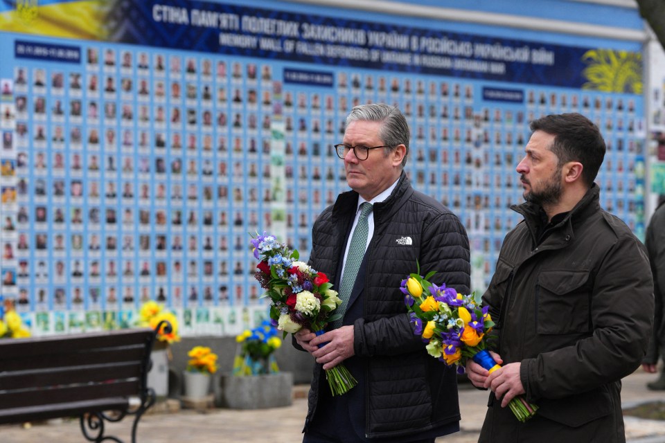 Keir Starmer and Volodymyr Zelensky laying wreaths at a memorial wall.