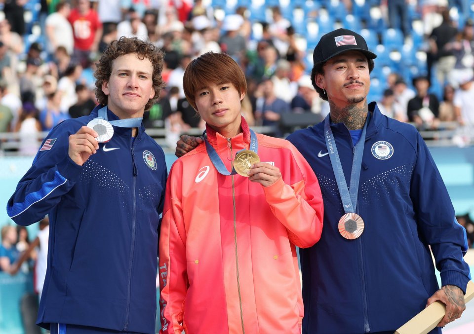 Three skateboarders at an awards ceremony; one with a gold medal, one with silver, and one with bronze.