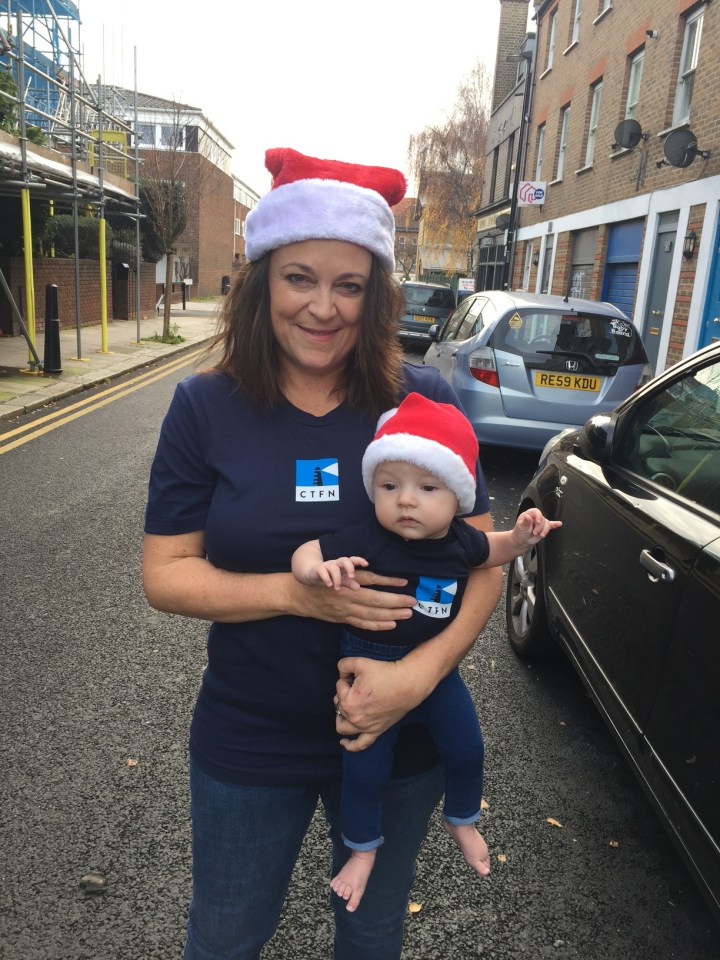 Woman in a Santa hat holding a baby in a Santa hat.