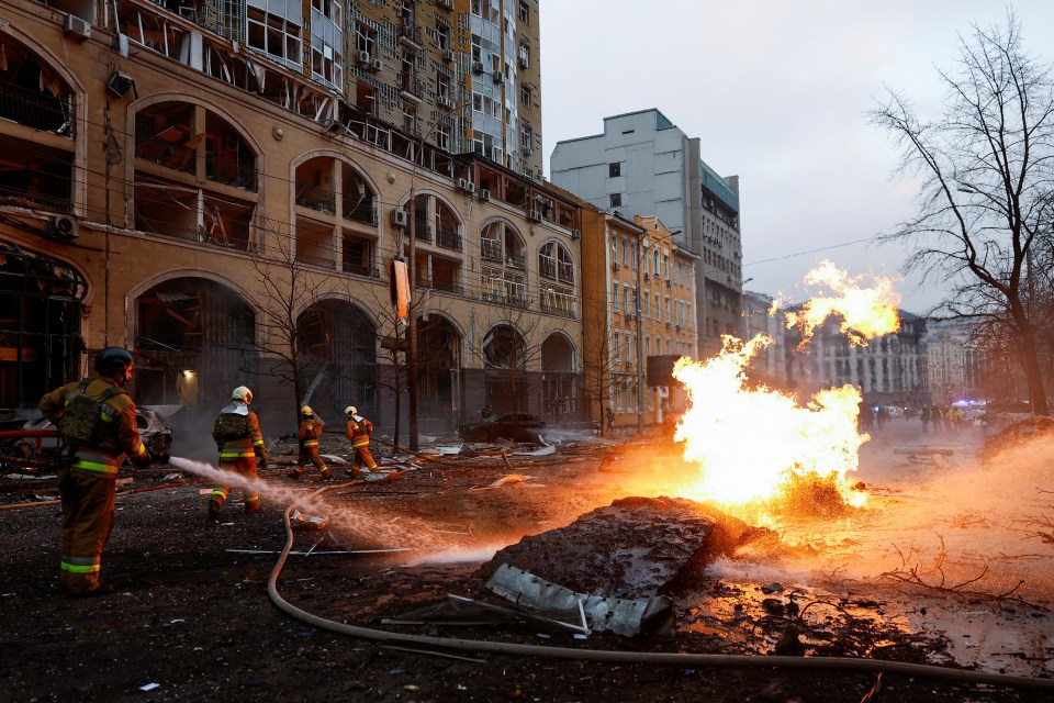 Firefighters extinguish a fire at the site of a destroyed building.