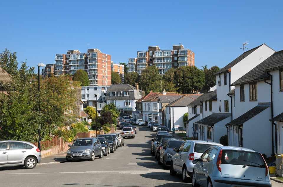 Residential street with parked cars and apartment buildings.