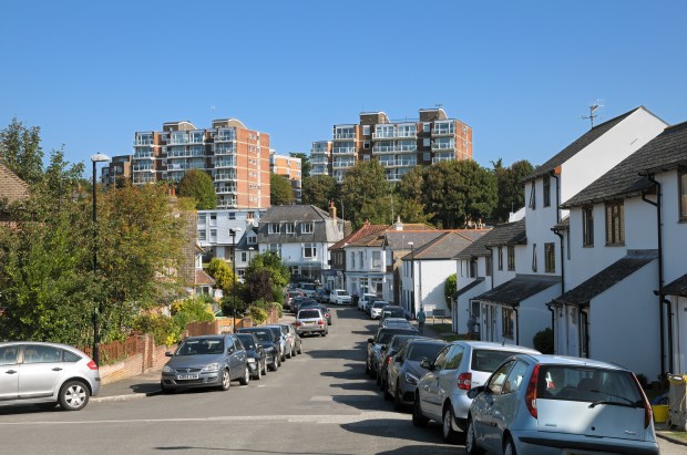 Residential street with parked cars and apartment buildings.