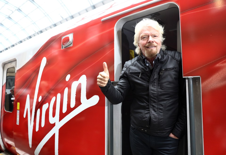 Richard Branson giving a thumbs up in a Virgin train.