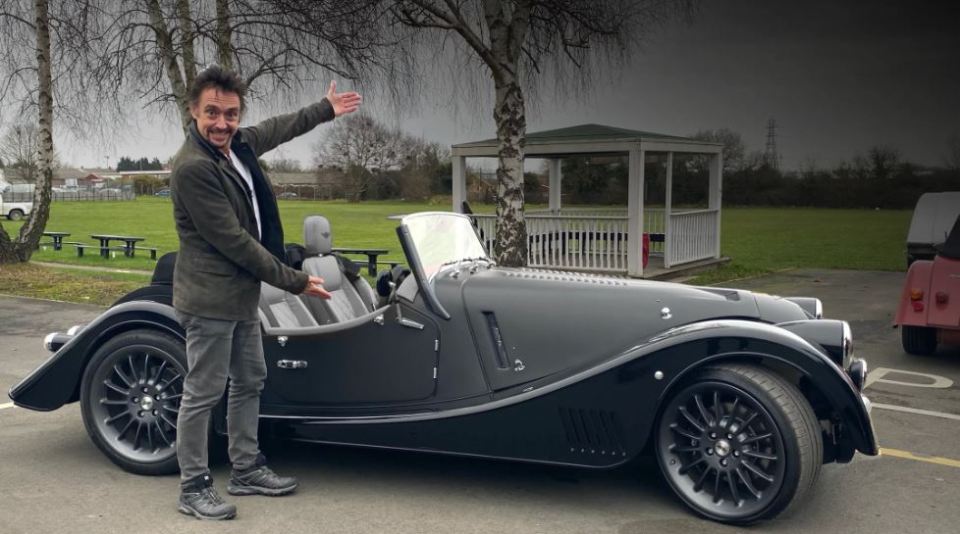 Richard Hammond standing next to his black sports car.